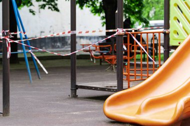 Çocukların oyun parkında sürmesi için bir slayt kırmızı bariyer bandıyla sarılmış. Açık havada yürüyüş yasağı, Coronavirus gribi virüsünün önlenmesi covid-19. Çalıntı mal. seçici odak