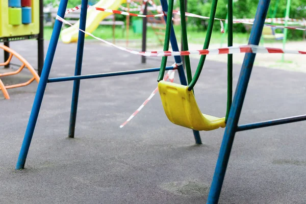 公園で黄色の子供たちのスイング赤いバリアテープで包まれた 屋外散歩の禁止 コロナウイルスインフルエンザウイルスの予防Covid エントリーなし 選択的焦点 — ストック写真