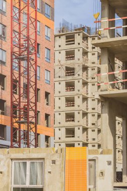 İnşaat aşamasında bir eve karşı kırmızı vinç parçası. Düşük gelirli genç aileler için endüstri konsepti. İpotek, iş, gayrimenkul kredisi.