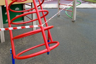 Oyun parkındaki çocuk spor metal yapısı kırmızı bant ile sarılmış. Dışarı çıkın. Açık havada yürüyüş yasağı, Coronavirus gribi virüsünün önlenmesi covid-19. uzak durma işareti.