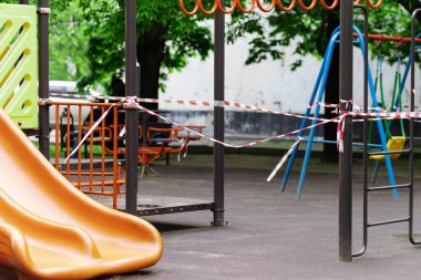 Çocukların parkta sürmesi için turuncu bir kaydırak kırmızı bariyer bandıyla sarılmış. Açık havada yürüyüş yasağı, Coronavirus gribi virüsünün önlenmesi covid-19. sağlıklı yaşam tarzı.