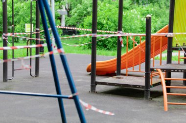 Küçük çocuklar için eğlence ve spor parkı kırmızı bariyer bandına sarılmış durumda. Dışarı çıkın. Açık havada yürüyüş yasağı, Coronavirus gribi virüsünün önlenmesi covid-19. seçici odak