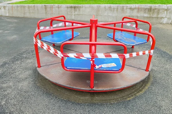 Rotes Karussell Auf Dem Spielplatz Umwickelt Mit Einem Absperrband Draußen lizenzfreie Stockfotos