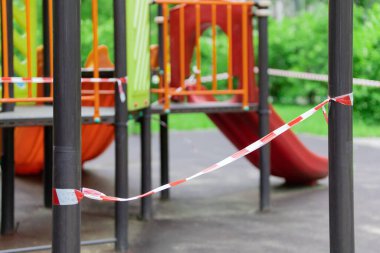 Küçük çocuklar için eğlence ve spor parkı kırmızı bariyer bandına sarılmış durumda. Açık havada yürüyüş yasağı, Coronavirus gribi virüsünün önlenmesi covid-19. Kilitleyin. seçici odak