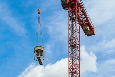 Çimento karıştırıcılı kırmızı vinç mavi gökyüzüne karşı beyaz bulutlar. Kapatın. Boşluğu kopyala.