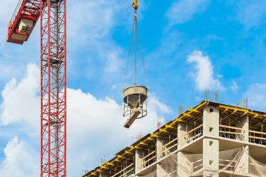 İnşaat aşamasında, üzerinde çimento harcı olan bir vinç ve mavi gökyüzü olan bir ev. Düşük gelirli genç aileler için endüstri konsepti. İpotek, iş, gayrimenkul kredisi.