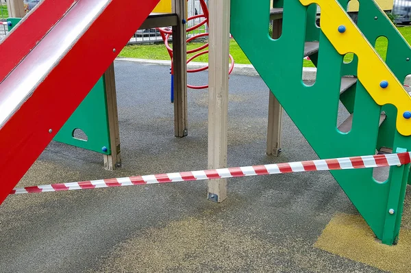 Eğlence parkındaki oyun parkındaki yeşil merdivenler kırmızı bant ile sarılmış. Açık havada yürüyüş yasağı, Coronavirus gribi virüsünün önlenmesi covid-19. Sağlık ve İlaç