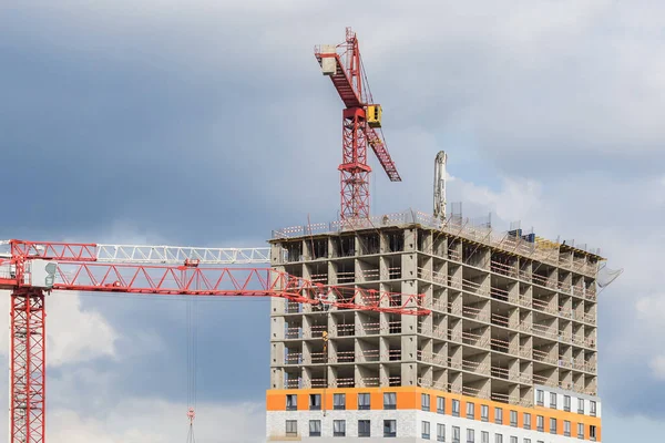 Several red cranes have been put to work on the construction of a modern multi-storey residential complex. Concept work for builder.