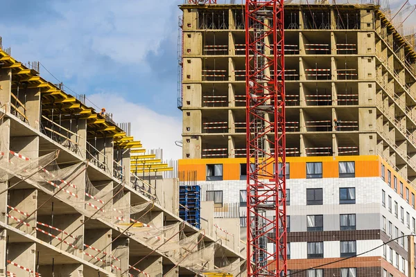 The part of red crane against a house and sky during the construction phase. Industry concept for low-income young families. Mortgage, business, real estate loan.