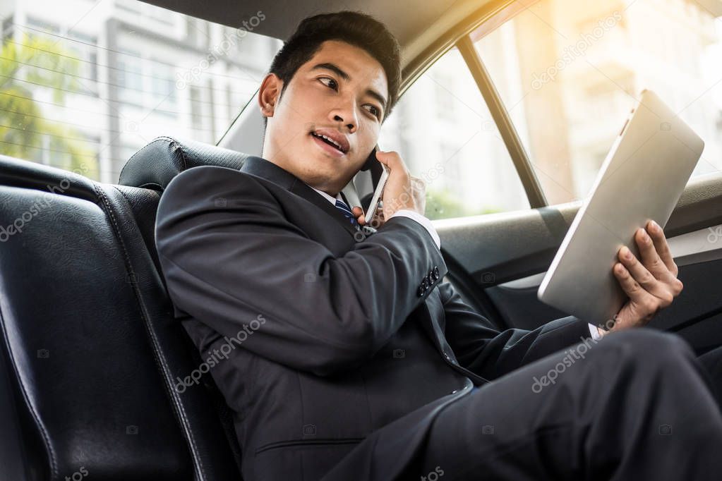 Attractive handsome young businessman using mobile smart phone in car.