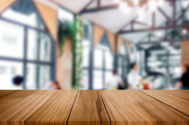 Seçilen odak boş kahverengi ahşap masa ve kafeterya bokeh görüntü ile arka plan bulanıklık. Fotomontaj veya ürün ekran.