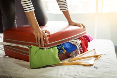 Kadın kırmızı bavulu tatil önce ambalaj için tüm giyim girmeye çalışıyoruz