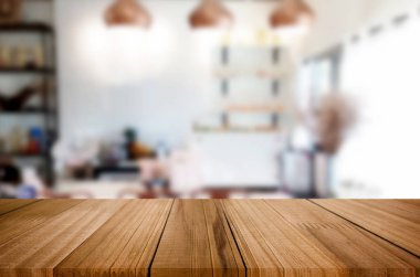 Seçilen odak boş kahverengi ahşap masa ve kafeterya bokeh görüntü ile arka plan bulanıklık. Fotomontaj veya ürün ekran.