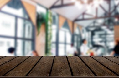 Seçilen odak boş kahverengi ahşap masa ve kafeterya bokeh görüntü ile arka plan bulanıklık. Fotomontaj veya ürün ekran.