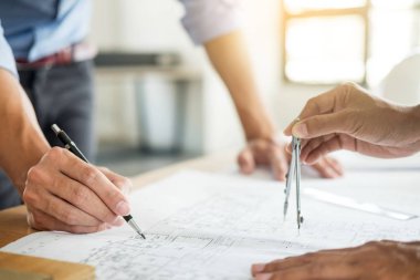 Yakın çekim, kişinin mühendis el çizim planı üzerinde mavi baskı mimar ekipmanlı, mimarlar tablo, takım çalışması ve iş akışı inşaat kavramı tartışmaya.