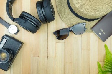 Gerekli seyahat aksesuarları, tropikal yaprak alanı olan ahşap arka plan üzerinde öğeleri. Seyahat tatil kavramı düz moda stil, üstten görünüm yatıyordu.