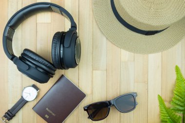 Gerekli seyahat aksesuarları, tropikal yaprak alanı olan ahşap arka plan üzerinde öğeleri. Seyahat tatil kavramı düz moda stil, üstten görünüm yatıyordu.