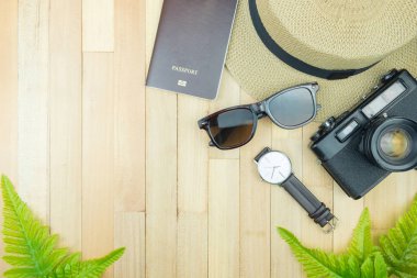 Gerekli seyahat aksesuarları, tropikal yaprak alanı olan ahşap arka plan üzerinde öğeleri. Seyahat tatil kavramı düz moda stil, üstten görünüm yatıyordu.