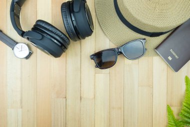 Gerekli seyahat aksesuarları, tropikal yaprak alanı olan ahşap arka plan üzerinde öğeleri. Seyahat tatil kavramı düz moda stil, üstten görünüm yatıyordu.