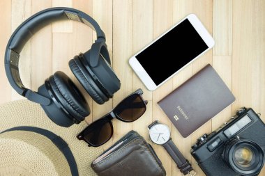 Gerekli seyahat aksesuarları, tropikal yaprak alanı olan ahşap arka plan üzerinde öğeleri. Seyahat tatil kavramı düz moda stil, üstten görünüm yatıyordu.