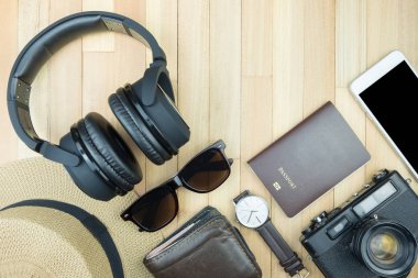 Gerekli seyahat aksesuarları, tropikal yaprak alanı olan ahşap arka plan üzerinde öğeleri. Seyahat tatil kavramı düz moda stil, üstten görünüm yatıyordu.