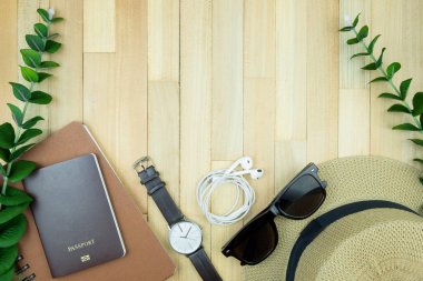 Gerekli seyahat aksesuarları, tropikal yaprak alanı olan ahşap arka plan üzerinde öğeleri. Seyahat tatil kavramı düz moda stil, üstten görünüm yatıyordu.