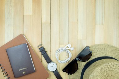 Gerekli seyahat aksesuarları, tropikal yaprak alanı olan ahşap arka plan üzerinde öğeleri. Seyahat tatil kavramı düz moda stil, üstten görünüm yatıyordu.