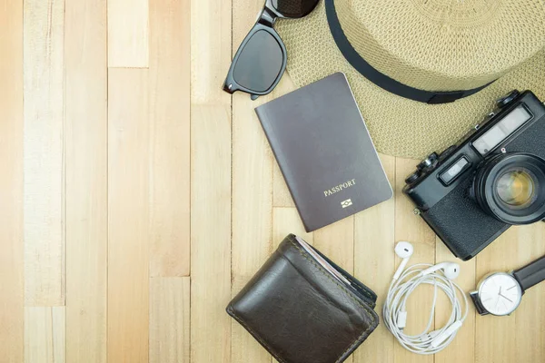 Gerekli seyahat aksesuarları, tropikal yaprak alanı olan ahşap arka plan üzerinde öğeleri. Seyahat tatil kavramı düz moda stil, üstten görünüm yatıyordu.