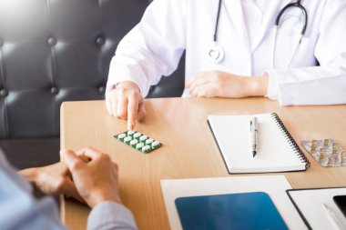 Tablet ilacın tutan el doktor ve hasta hastane odasında açıklamak.