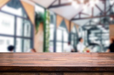 Seçilen odak boş kahverengi ahşap masa ve kafeterya bokeh görüntü ile arka plan bulanıklık. Fotomontaj veya ürün ekran.
