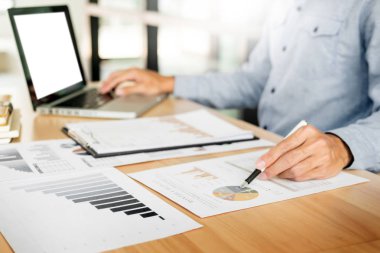 Ofiste çalışan işadamı bilgisayarında, tabletinde ve çalışma masasında veri dokümanlarıyla çalışıyor..