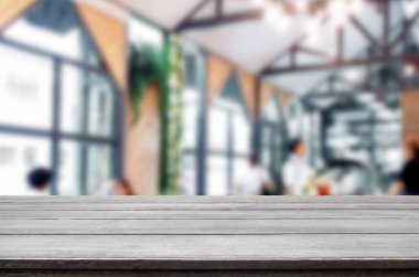 Seçilen odak boş kahverengi ahşap masa ve kafeterya bokeh görüntü ile arka plan bulanıklık. Fotomontaj veya ürün ekran.