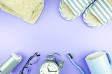 madeni eşya saat düz yatıyordu kompozisyon diş fırçası gözlük, mavi ve mor menekşe kavramı üzerinde havlu ve terlik üstten görünüm
