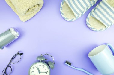 madeni eşya saat düz yatıyordu kompozisyon diş fırçası gözlük, mavi ve mor menekşe kavramı üzerinde havlu ve terlik üstten görünüm