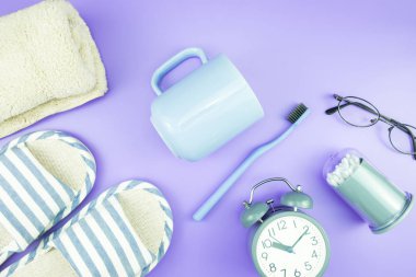 madeni eşya saat düz yatıyordu kompozisyon diş fırçası gözlük, mavi ve mor menekşe kavramı üzerinde havlu ve terlik üstten görünüm