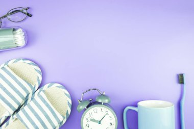 madeni eşya saat düz yatıyordu kompozisyon diş fırçası gözlük, mavi ve mor menekşe kavramı üzerinde havlu ve terlik üstten görünüm