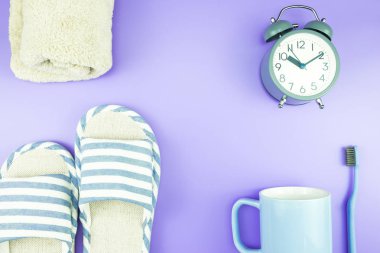 madeni eşya saat düz yatıyordu kompozisyon diş fırçası gözlük, mavi ve mor menekşe kavramı üzerinde havlu ve terlik üstten görünüm