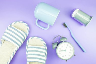 madeni eşya saat düz yatıyordu kompozisyon diş fırçası gözlük, mavi ve mor menekşe kavramı üzerinde havlu ve terlik üstten görünüm