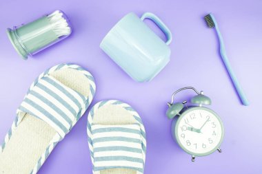 madeni eşya saat düz yatıyordu kompozisyon diş fırçası gözlük, mavi ve mor menekşe kavramı üzerinde havlu ve terlik üstten görünüm