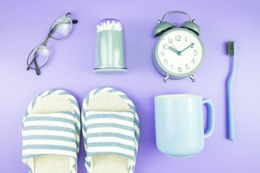 madeni eşya saat düz yatıyordu kompozisyon diş fırçası gözlük, mavi ve mor menekşe kavramı üzerinde havlu ve terlik üstten görünüm