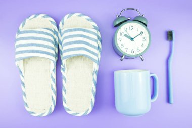 madeni eşya saat düz yatıyordu kompozisyon diş fırçası gözlük, mavi ve mor menekşe kavramı üzerinde havlu ve terlik üstten görünüm