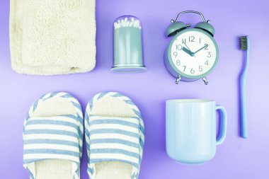 madeni eşya saat düz yatıyordu kompozisyon diş fırçası gözlük, mavi ve mor menekşe kavramı üzerinde havlu ve terlik üstten görünüm