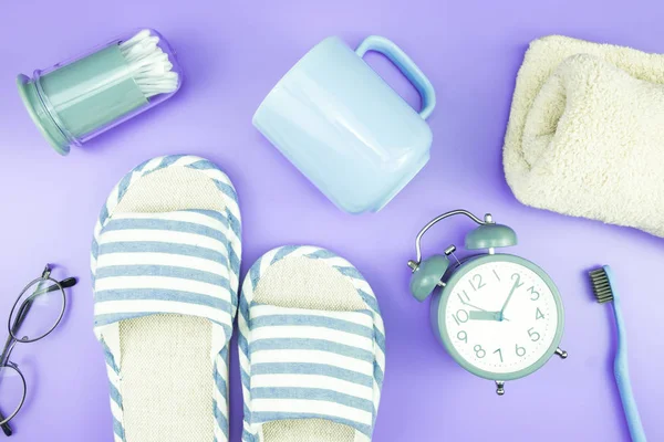 madeni eşya saat düz yatıyordu kompozisyon diş fırçası gözlük, mavi ve mor menekşe kavramı üzerinde havlu ve terlik üstten görünüm