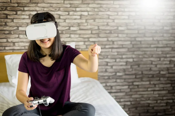 Mutlu gülümseyen genç kadın evde yatakta 360 Vr kulaklık gözlük sanal gerçekliğin kullanırken en iyi deneyimleri elde ederken oyun oynama