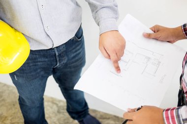 Yakın çekim, kişinin mühendis el çizim planı üzerinde mavi baskı mimar ekipmanlı, mimarlar tablo, takım çalışması ve iş akışı inşaat kavramı tartışmaya.