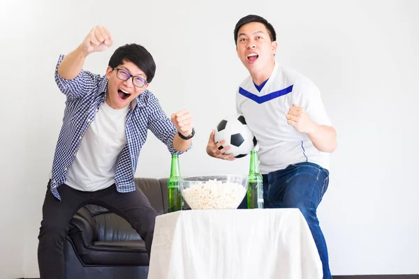 friendship, sports and entertainment concept - happy male friends cheering and watching tv together at home supporting world cup football team win.