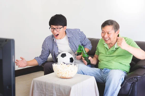 friendship, sports and entertainment concept - happy male friends cheering and watching tv together at home supporting world cup football team win.