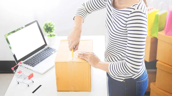 e-commerce delivery concept and online selling start up small business owner packing in the card box at workplace. freelance woman seller prepare product for packaging process at shop.