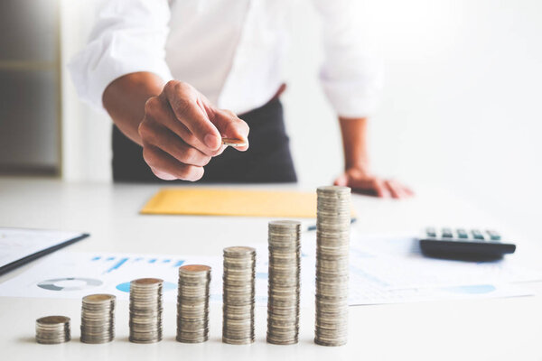 Midsection of businessman hand put stacking coins at on Increasing coin office desk, Currency, Investment, Savings, financial concept.