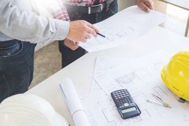 Yakın çekim, kişinin mühendis el çizim planı üzerinde mavi baskı mimar ekipmanlı, mimarlar tablo, takım çalışması ve iş akışı inşaat kavramı tartışmaya.